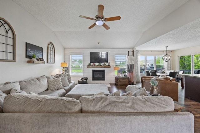 living room featuring a textured ceiling, a glass covered fireplace, dark wood-style floors, and lofted ceiling