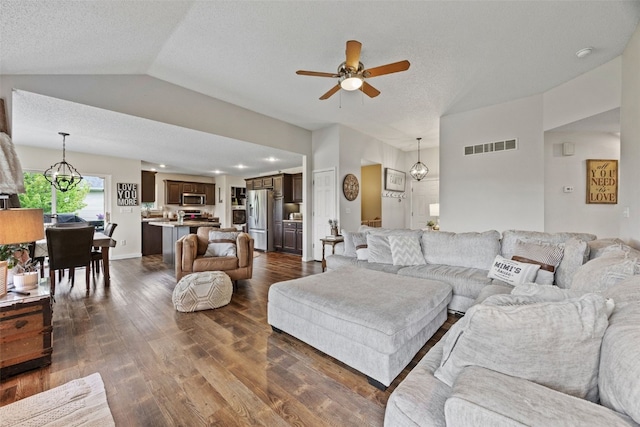 living room with a textured ceiling, visible vents, dark wood finished floors, ceiling fan with notable chandelier, and lofted ceiling