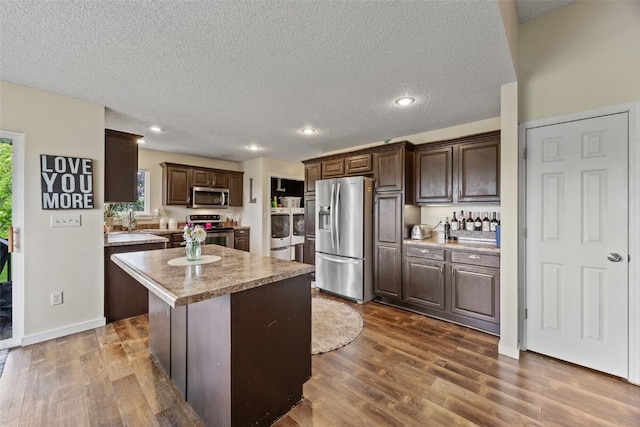 kitchen featuring light countertops, dark brown cabinetry, stainless steel appliances, and washer and dryer