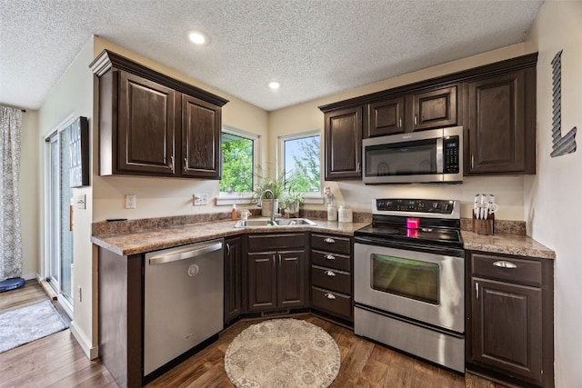 kitchen featuring a sink, a textured ceiling, dark brown cabinets, and stainless steel appliances