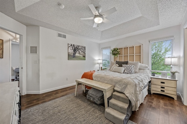 bedroom with dark wood-style flooring, a textured ceiling, visible vents, and multiple windows