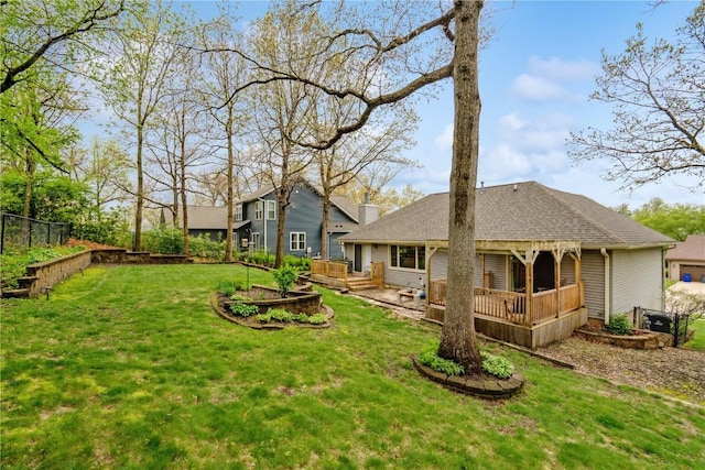 back of property with a shingled roof, fence, a yard, and a deck
