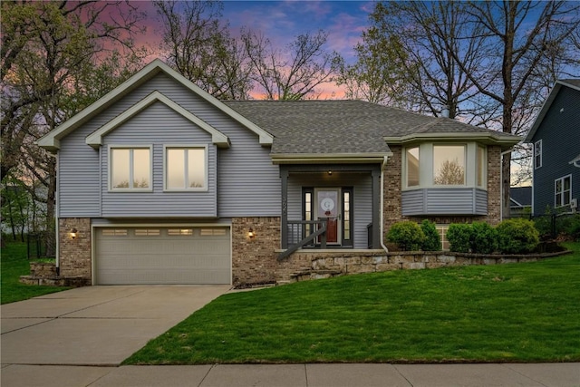 view of front of house with a yard, an attached garage, concrete driveway, and brick siding