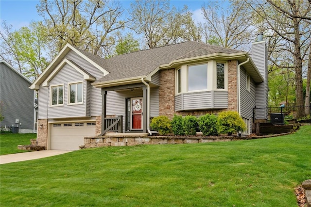 raised ranch with a garage, a chimney, driveway, and a front lawn