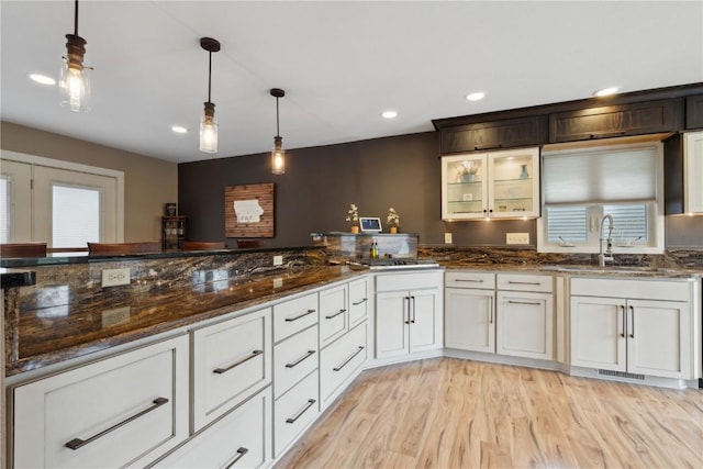 interior space with visible vents, decorative light fixtures, a sink, light wood finished floors, and recessed lighting