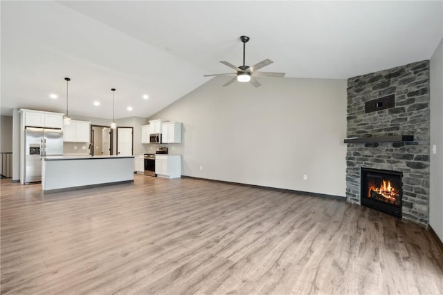 unfurnished living room featuring a ceiling fan, a fireplace, vaulted ceiling, light wood-type flooring, and recessed lighting
