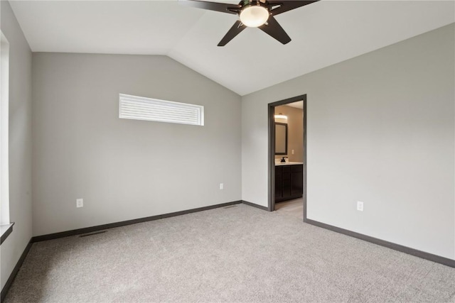 spare room featuring baseboards, ceiling fan, light carpet, and vaulted ceiling