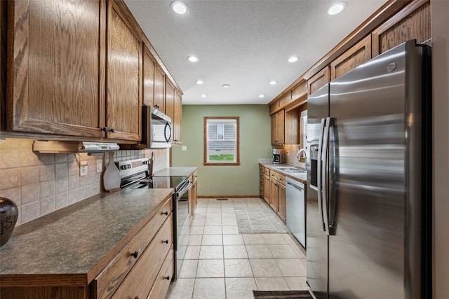 kitchen with baseboards, recessed lighting, a sink, backsplash, and stainless steel appliances