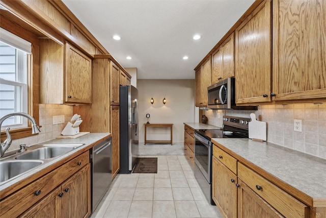 kitchen featuring recessed lighting, brown cabinets, tasteful backsplash, a sink, and stainless steel appliances