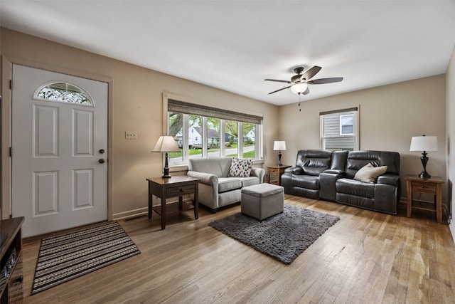 living room featuring a ceiling fan, a wealth of natural light, and light wood-style flooring