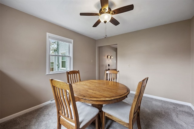 carpeted dining area with baseboards and ceiling fan