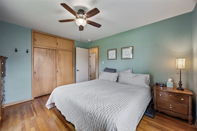 bedroom with baseboards, a ceiling fan, a closet, and wood finished floors