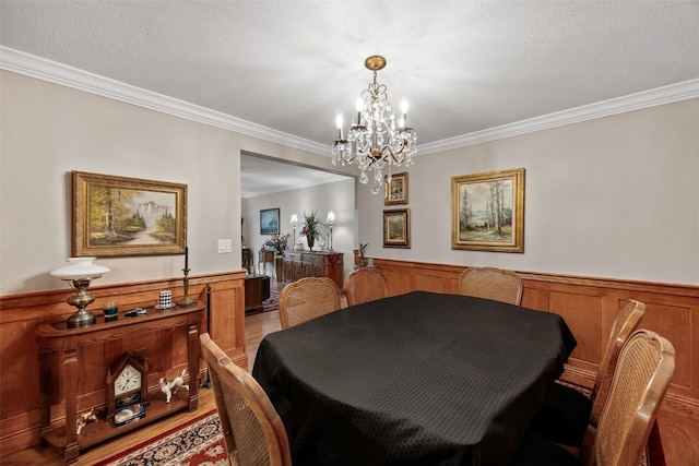 dining room featuring ornamental molding, wainscoting, and a notable chandelier