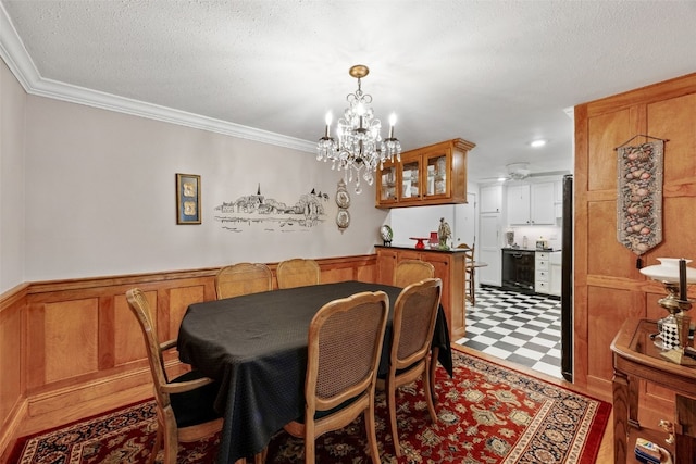 dining area with a textured ceiling, crown molding, wainscoting, tile patterned floors, and a notable chandelier