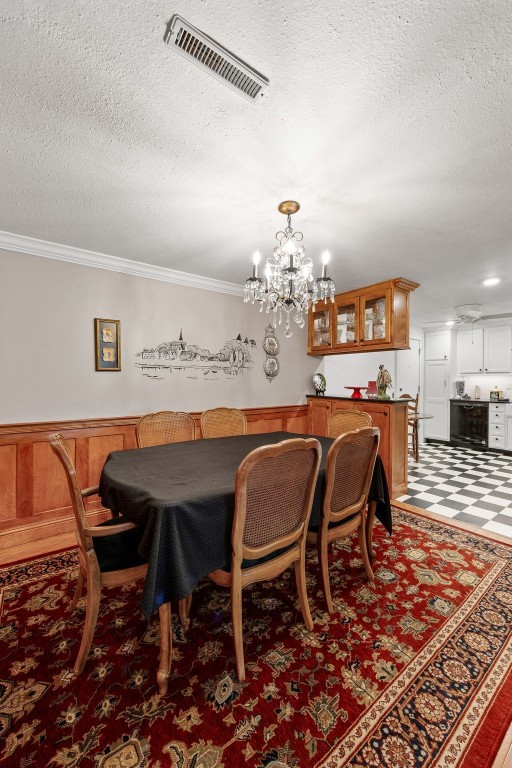 dining room featuring visible vents, a textured ceiling, crown molding, and an inviting chandelier