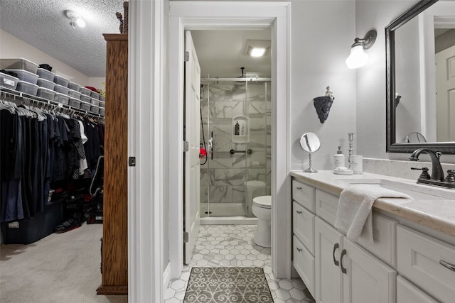 bathroom with vanity, toilet, a textured ceiling, a spacious closet, and a shower stall