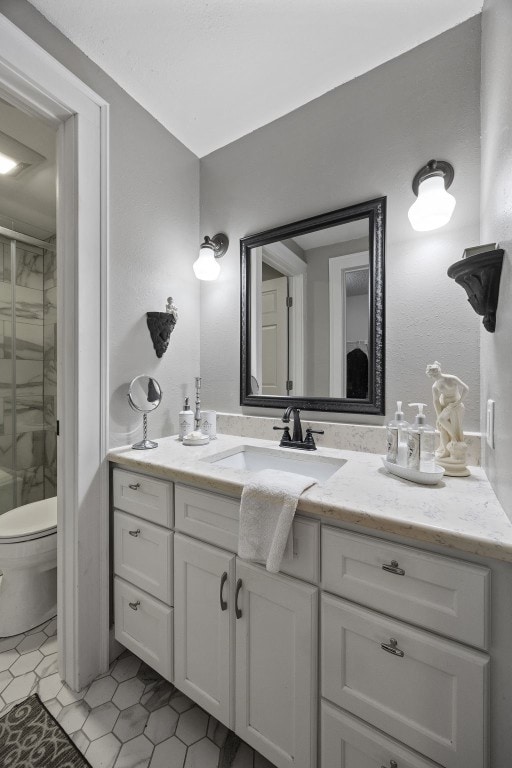 bathroom with vanity, tile patterned floors, a shower with door, and toilet