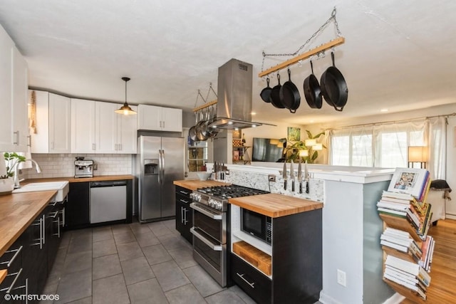 kitchen with butcher block countertops, white cabinets, island exhaust hood, a sink, and stainless steel appliances
