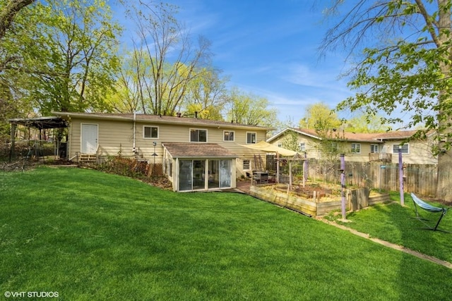 rear view of house with a lawn, fence, a garden, and a sunroom