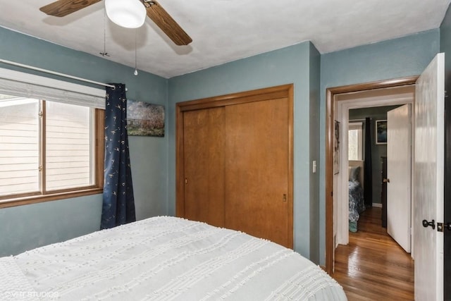bedroom with a ceiling fan, wood finished floors, and a closet
