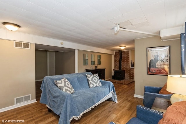living area with visible vents, a wood stove, baseboards, and wood finished floors