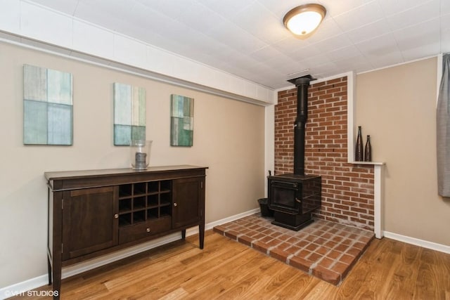 living room featuring baseboards, wood finished floors, and a wood stove