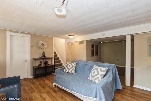 living room with stairs, baseboards, visible vents, and wood finished floors