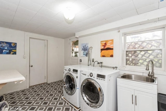 washroom with cabinet space, a wealth of natural light, a sink, and washing machine and clothes dryer