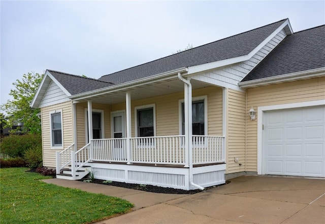view of front of house featuring roof with shingles, covered porch, an attached garage, and concrete driveway