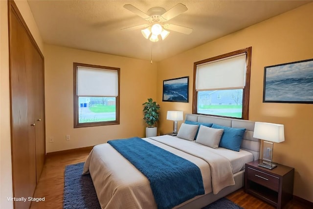 bedroom featuring baseboards, multiple windows, ceiling fan, and a closet