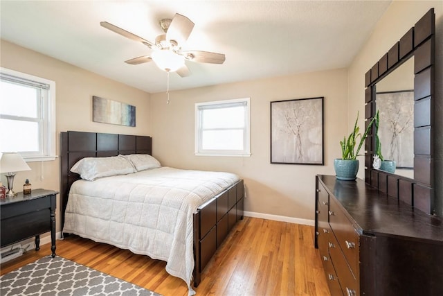 bedroom with baseboards, light wood finished floors, ceiling fan, and multiple windows