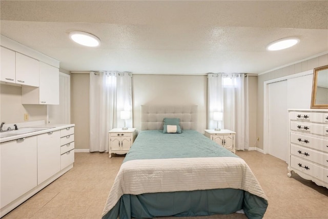 bedroom with baseboards, a textured ceiling, and light floors