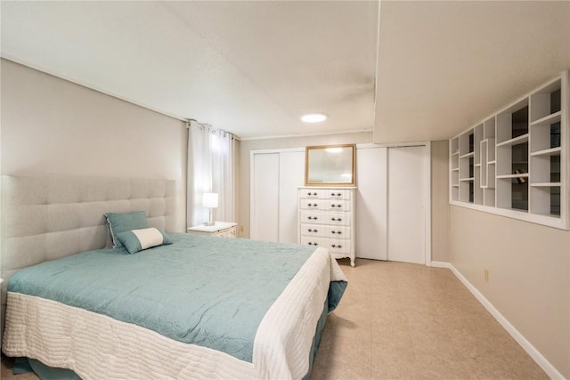 bedroom featuring baseboards and two closets