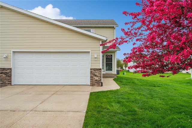 view of front facade featuring brick siding, a garage, driveway, and a front lawn