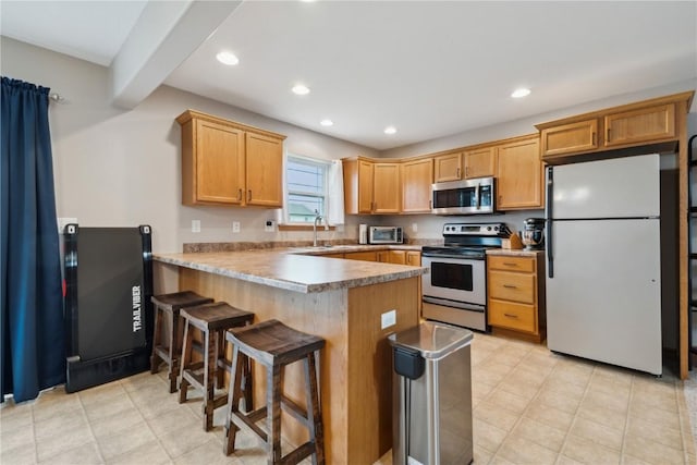 kitchen with a kitchen bar, appliances with stainless steel finishes, light tile patterned floors, a peninsula, and recessed lighting