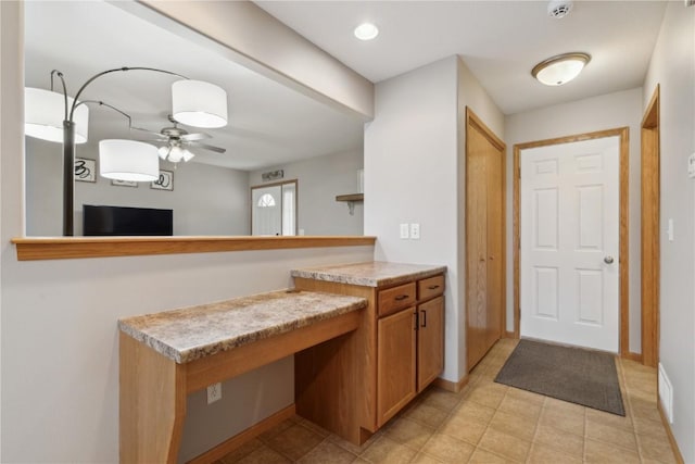kitchen with light tile patterned flooring, light countertops, brown cabinetry, a ceiling fan, and visible vents