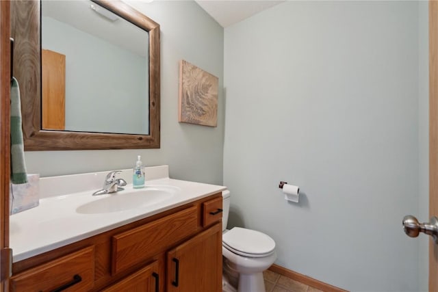 half bath featuring vanity, baseboards, tile patterned flooring, and toilet