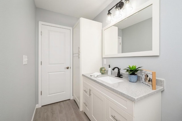 bathroom with baseboards, wood finished floors, and vanity