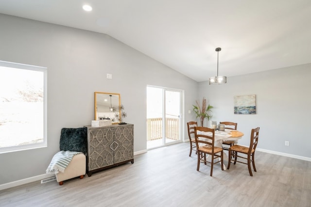 dining area with baseboards, wood finished floors, visible vents, and high vaulted ceiling