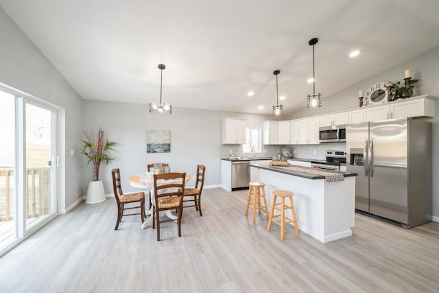 kitchen with light wood-style flooring, appliances with stainless steel finishes, lofted ceiling, and a kitchen island