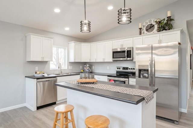 kitchen with dark countertops, white cabinetry, a sink, light wood-style flooring, and stainless steel appliances