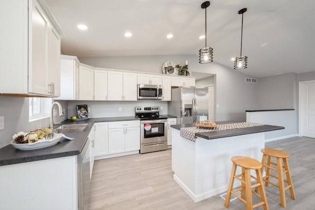 kitchen featuring dark countertops, a sink, stainless steel appliances, light wood-type flooring, and visible vents