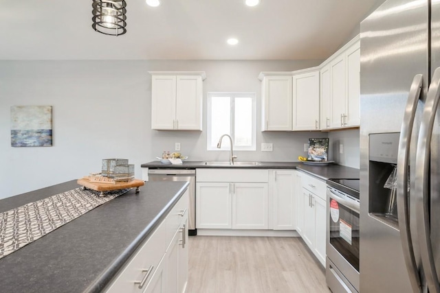 kitchen featuring dark countertops, a sink, stainless steel appliances, recessed lighting, and white cabinetry