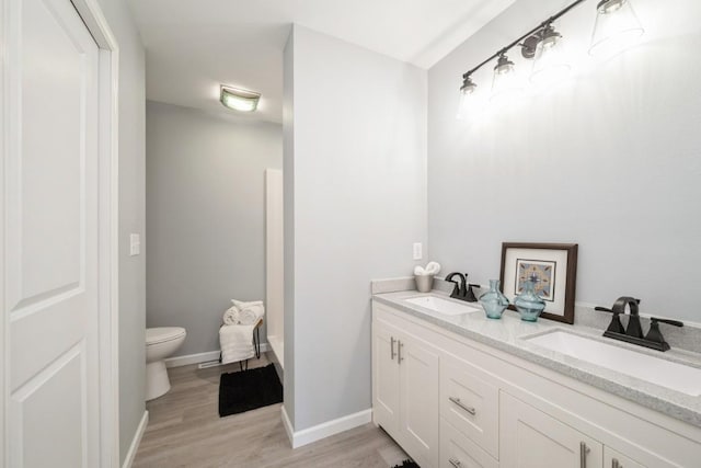 full bathroom featuring double vanity, a sink, wood finished floors, and toilet