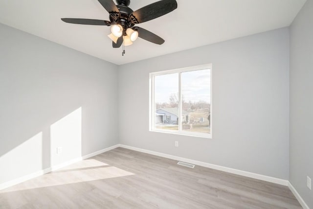 empty room featuring baseboards, light wood-style flooring, ceiling fan, and visible vents