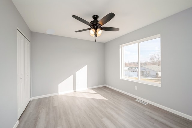 empty room featuring baseboards, ceiling fan, visible vents, and wood finished floors