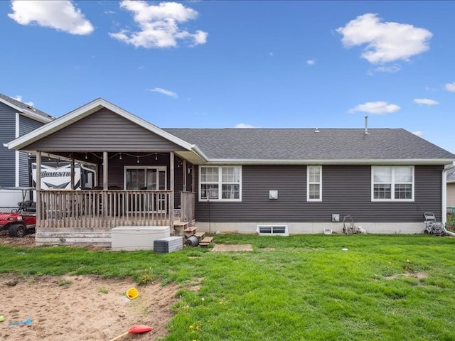 back of property with a lawn and roof with shingles
