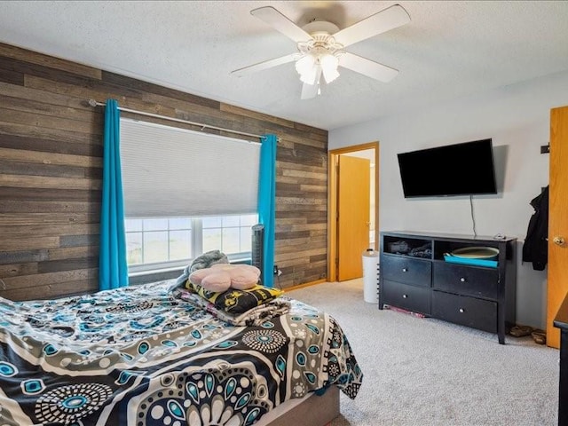 bedroom with wooden walls, carpet floors, ceiling fan, and a textured ceiling