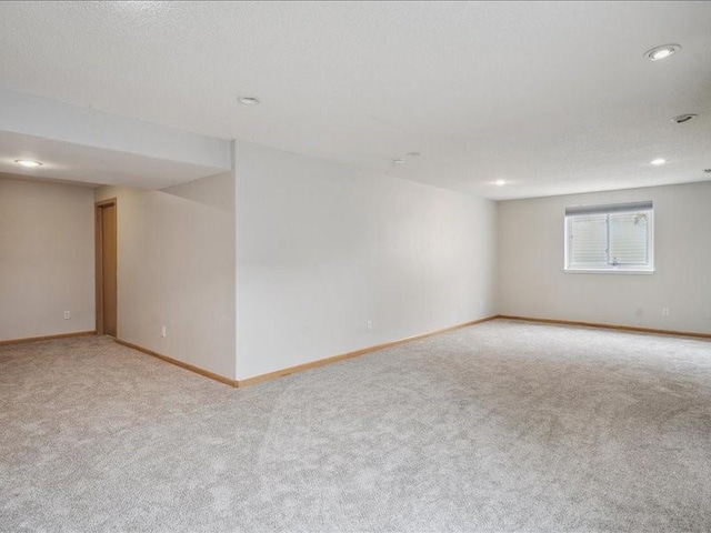basement with light colored carpet, recessed lighting, and baseboards