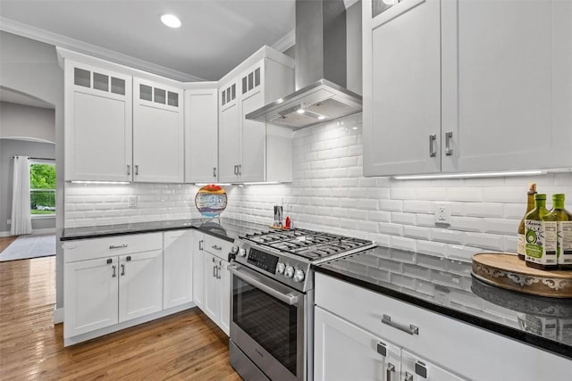 917 Robin Rd, Iowa City, IA 52246 - kitchen featuring arched walkways, gas range, white cabinetry, and wall chimney exhaust hood